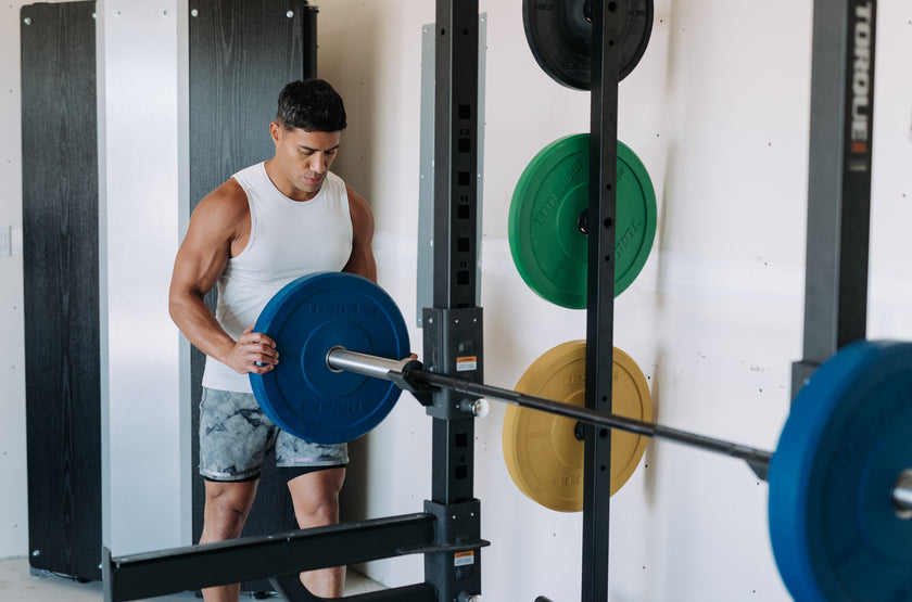 Man Loading Colored Bumper Plates Onto Barbell